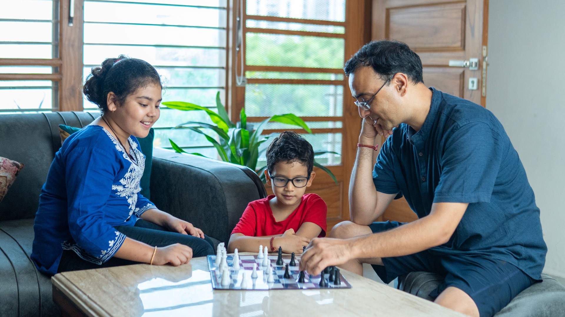 Father playing chess with children at home