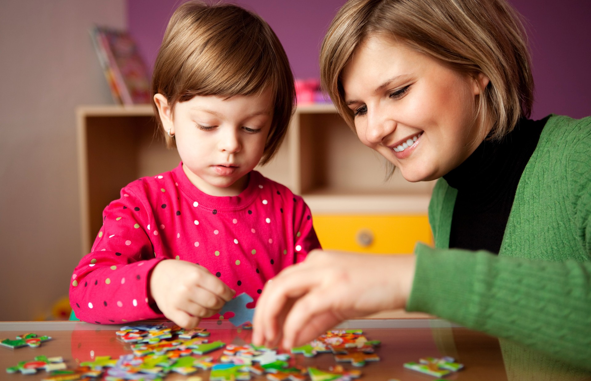 Mother helping her daughter with puzzle